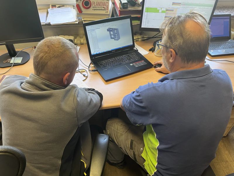 Dva kolegové u počítače s technickým modelem
